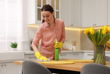 Spring cleaning. Young woman tidying up kitchen at home