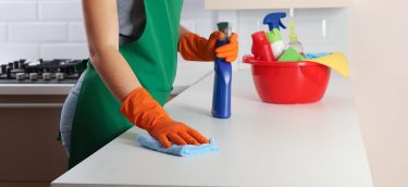 Woman In Protective Gloves Cleaning Kitchen Table With Rag, Indo Woman in protective gloves cleaning kitchen table with rag, indoors