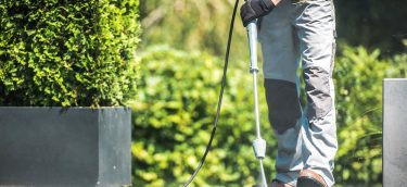 Patio Pressure Cleaning. Caucasian Men Washing His Concrete Floo Patio Pressure Cleaning. Caucasian Men Washing His Concrete Floor Patio Using High Pressured Water Cleaner.